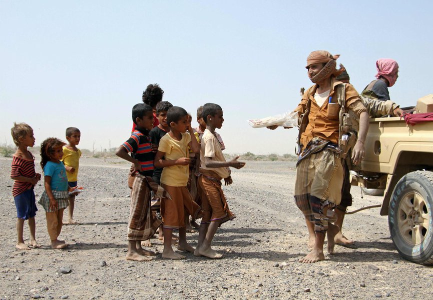 Pro-government fighters give food to Yemeni children on the road leading to the southwestern port city of Mokha on January 26, 2017. Yemeni rebels are putting up fierce resistance in a key Red Sea (Foto: Giuliana Miranda) Pro-government fighters give food to Yemeni children on the road leading to the southwestern port city of Mokha on January 26, 2017. Yemeni rebels are putting up fierce resistance in a key Red Sea