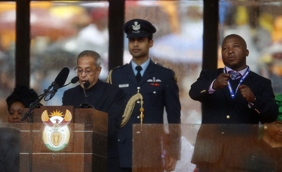 India's President Pranab Mukherjee speaks at the podium as a sign language interpreter (R) punches the air beside him during a memorial service for late South African President Nelson Mandela at the FNB soccer stadium in Johannesburg December 10, 2013. Th (Foto: Gisele Federicce) India's President Pranab Mukherjee speaks at the podium as a sign language interpreter (R) punches the air beside him during a memorial service for late South African President Nelson Mandela at the FNB soccer stadium in Johannesburg December 10, 2013. Th