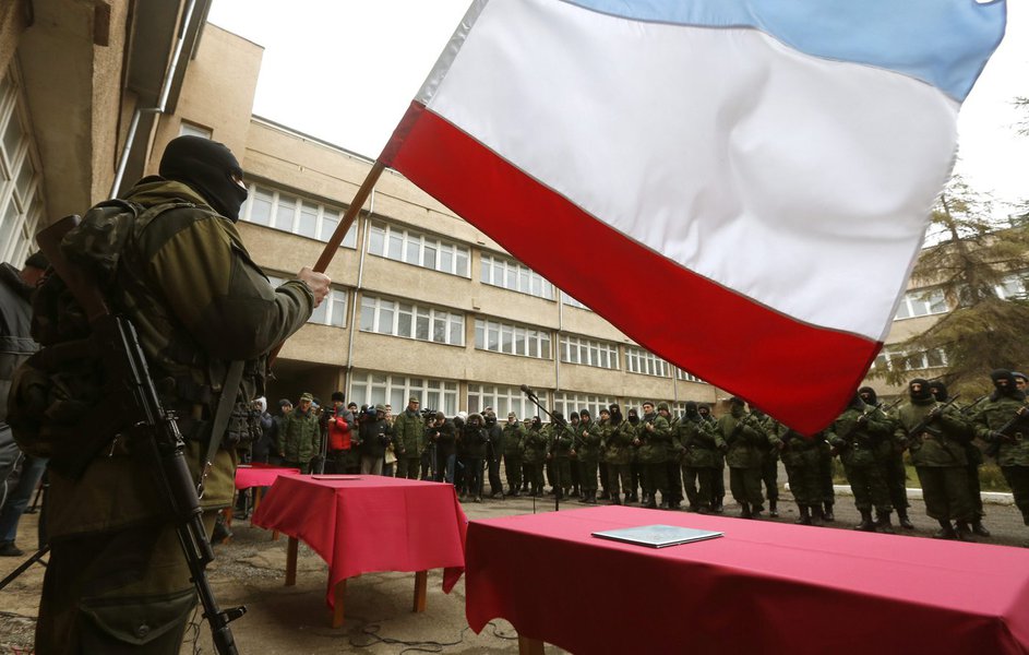 An armed man, believed to be a Russian serviceman, holds a Crimea flag as members of a pro-Russian self defence unit stand in a formation before taking an oath to Crimea government in Simferopol March 10, 2014. Russian forces consolidated their hold on Uk (Foto: Gisele Federicce) An armed man, believed to be a Russian serviceman, holds a Crimea flag as members of a pro-Russian self defence unit stand in a formation before taking an oath to Crimea government in Simferopol March 10, 2014. Russian forces consolidated their hold on Uk