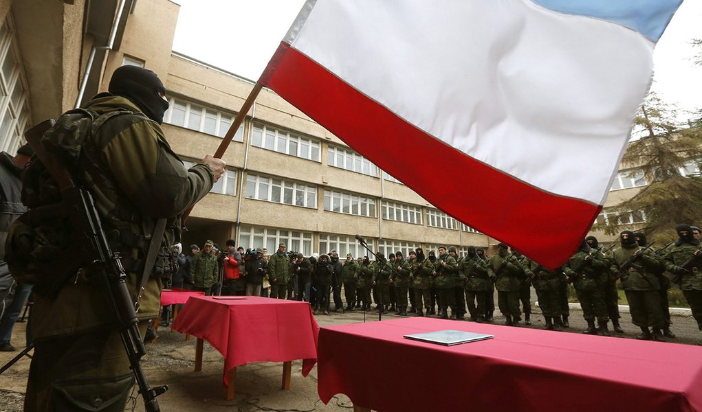 An armed man, believed to be a Russian serviceman, holds a Crimea flag as members of a pro-Russian self defence unit stand in a formation before taking an oath to Crimea government in Simferopol March 10, 2014. Russian forces consolidated their hold on Uk (Foto: Leonardo Attuch) An armed man, believed to be a Russian serviceman, holds a Crimea flag as members of a pro-Russian self defence unit stand in a formation before taking an oath to Crimea government in Simferopol March 10, 2014. Russian forces consolidated their hold on Uk