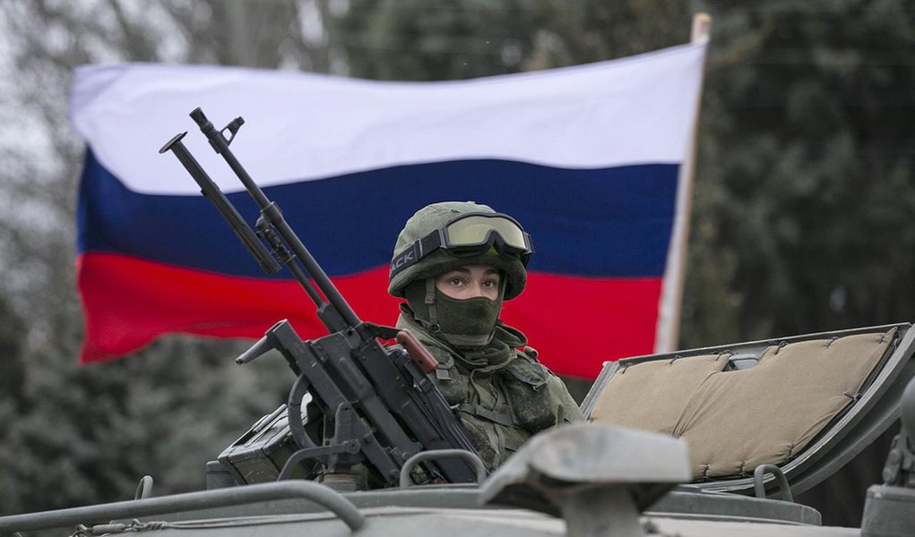 A pro-Russian man (not seen) holds a Russian flag behind an armed servicemen on top of a Russian army vehicle outside a Ukrainian border guard post in the Crimean town of Balaclava March 1, 2014. Ukraine accused Russia on Saturday of sending thousands of (Foto: Valter Lima) A pro-Russian man (not seen) holds a Russian flag behind an armed servicemen on top of a Russian army vehicle outside a Ukrainian border guard post in the Crimean town of Balaclava March 1, 2014. Ukraine accused Russia on Saturday of sending thousands of
