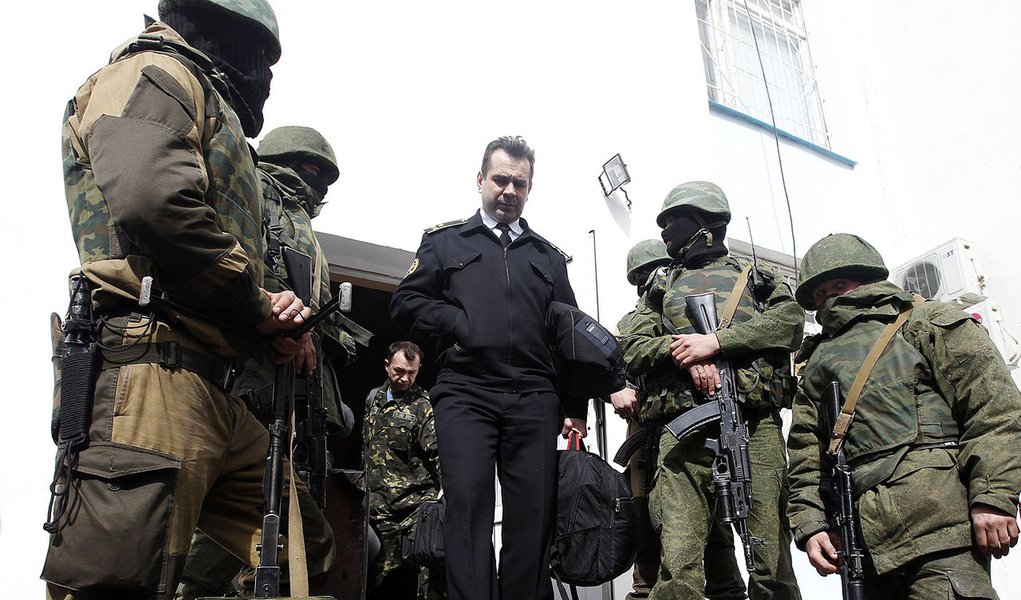 A Ukrainian naval officer (C) passes by armed men, believed to be Russian servicemen, as he leaves the naval headquarters in Sevastopol, March 19, 2014. Three Russian flags were flying at one of the entrances to Ukraine's naval headquarters in the Crimean (Foto: Roberta Namour) A Ukrainian naval officer (C) passes by armed men, believed to be Russian servicemen, as he leaves the naval headquarters in Sevastopol, March 19, 2014. Three Russian flags were flying at one of the entrances to Ukraine's naval headquarters in the Crimean