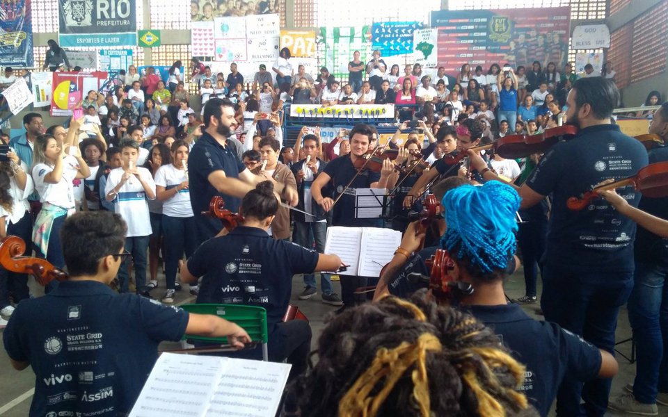 As três formações do Projeto Orquestra Maré do Amanhã se apresentarão neste domingo (17), pela primeira vez em um concerto próprio, no principal palco da música erudita do Rio de Janeiro: o Theatro Municipal. Ao todo, são 77 jovens que integram as orquestras infantil, com idades entre 5 e 7 anos, a infantojuvenil, até os 13 anos, e a orquestra principal, com 30 jovens a partir de 16 anos. O criador do projeto, Carlos Eduardo Prazeres, explica que o Maré do Amanhã atende atualmente 2.200 crianças de todas as comunidades que integram o complexo, matriculadas em escolas de ensino fundamental e educação infantil, que fazem musicalização (Foto: Leonardo Attuch) As três formações do Projeto Orquestra Maré do Amanhã se apresentarão neste domingo (17), pela primeira vez em um concerto próprio, no principal palco da música erudita do Rio de Janeiro: o Theatro Municipal. Ao todo, são 77 jovens que integram as orquestras infantil, com idades entre 5 e 7 anos, a infantojuvenil, até os 13 anos, e a orquestra principal, com 30 jovens a partir de 16 anos. O criador do projeto, Carlos Eduardo Prazeres, explica que o Maré do Amanhã atende atualmente 2.200 crianças de todas as comunidades que integram o complexo, matriculadas em escolas de ensino fundamental e educação infantil, que fazem musicalização