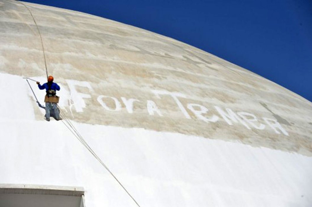O operário que pintou um “Fora Temer” monumental na parede do Museu Nacional de Brasília enquanto trabalhava na pintura do prédio foi demitido na sequência de seu protesto; a empresa contratada para a restauração do edifício, RVA Comércio e Serviços de Construção, confirmou a dispensa (Foto: Giuliana Miranda) O operário que pintou um “Fora Temer” monumental na parede do Museu Nacional de Brasília enquanto trabalhava na pintura do prédio foi demitido na sequência de seu protesto; a empresa contratada para a restauração do edifício, RVA Comércio e Serviços de Construção, confirmou a dispensa