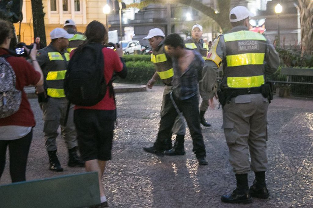 Jornalista Douglas Freitas, da organização Amigos da Terra Brasil, foi detido no ato no Santander Cultural que terminou com bombas da Brigada Militar, em Porto Alegre; ele divulgou um vídeo no qual a sua prisão é gravada; nele, Freitas começa registrando a detenção de um homem pela polícia, no momento em que bombas de gás explodiam na Praça da Alfândega; ao aproximar-se do grupo de policiais, entretanto, um brigadiano ordena que ele suspenda a gravação; "Foi dito para ti ir para lá", ordena o oficial; o jornalista segue gravando, e pergunta para onde o homem imobilizado será encaminhado e qual é o motivo da prisão (Foto: Leonardo Lucena) Jornalista Douglas Freitas, da organização Amigos da Terra Brasil, foi detido no ato no Santander Cultural que terminou com bombas da Brigada Militar, em Porto Alegre; ele divulgou um vídeo no qual a sua prisão é gravada; nele, Freitas começa registrando a detenção de um homem pela polícia, no momento em que bombas de gás explodiam na Praça da Alfândega; ao aproximar-se do grupo de policiais, entretanto, um brigadiano ordena que ele suspenda a gravação; "Foi dito para ti ir para lá", ordena o oficial; o jornalista segue gravando, e pergunta para onde o homem imobilizado será encaminhado e qual é o motivo da prisão