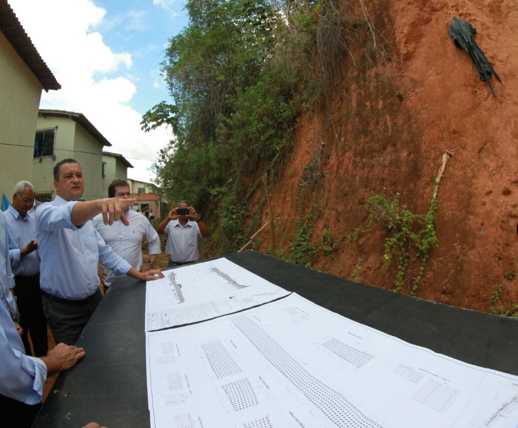 O governador Rui Costa assinou nesta segunda-feira ordem de serviço para início das obras de contenção de encosta na Rua da Represa, no bairro de Pirajá, em Salvador; mais de 50 famílias serão beneficiadas pela intervenção que terá investimento de R$ 2,4 milhões; "Hoje estamos fazendo algo que para mim tem um valor simbólico muito grande. Priorizamos encostas porque queremos salvar vidas, de adultos e crianças, e dar mais tranquilidade a essas pessoas. Não queremos que ninguém tenha que sair de suas casas com medo da chuva. Se no passado não houve cuidado, hoje nós temos que ter", disse Rui (Foto: Romulo Faro) O governador Rui Costa assinou nesta segunda-feira ordem de serviço para início das obras de contenção de encosta na Rua da Represa, no bairro de Pirajá, em Salvador; mais de 50 famílias serão beneficiadas pela intervenção que terá investimento de R$ 2,4 milhões; "Hoje estamos fazendo algo que para mim tem um valor simbólico muito grande. Priorizamos encostas porque queremos salvar vidas, de adultos e crianças, e dar mais tranquilidade a essas pessoas. Não queremos que ninguém tenha que sair de suas casas com medo da chuva. Se no passado não houve cuidado, hoje nós temos que ter", disse Rui