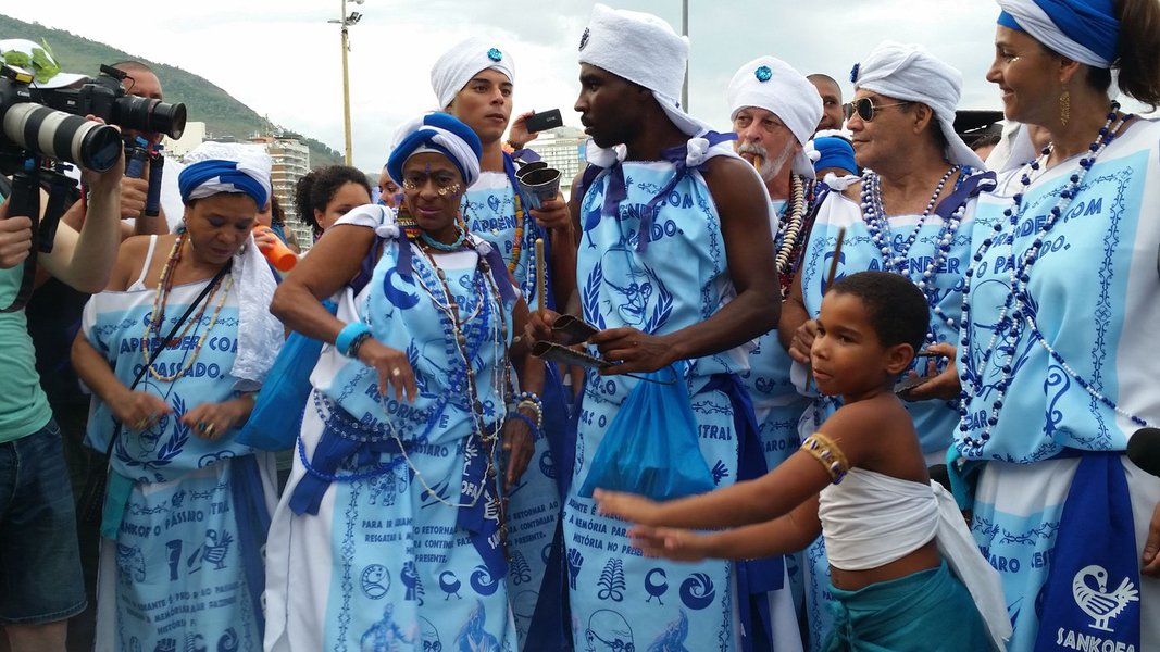 Três grupos de afoxé do carnaval carioca se uniram e fizeram o desfile juntos hoje (27) em Copacabana. O Afoxé Filhos de Gandhi, pioneiro na cidade, chamou os “filhos” Afoxé Raízes Africanas e Afoxé Ilê Alá para o cortejo de azul e branco pela Avenida Atlântida, que saiu por volta de 18h; fundado em 1951, o Filhos de Gandhi é o primeiro afoxé do Rio de Janeiro. Ele foi criado apenas dois anos depois do grupo de Salvador que leva o mesmo nome; “Lá são só homens, aqui o homem continua o cérebro, mas a mulher é o coração. Somos pioneiros no Rio de Janeiro, é o primeiro afoxé da cidade”, afirma a diretora de produção do grupo carioca, Ya Regina (Foto: Aquiles Lins) Três grupos de afoxé do carnaval carioca se uniram e fizeram o desfile juntos hoje (27) em Copacabana. O Afoxé Filhos de Gandhi, pioneiro na cidade, chamou os “filhos” Afoxé Raízes Africanas e Afoxé Ilê Alá para o cortejo de azul e branco pela Avenida Atlântida, que saiu por volta de 18h; fundado em 1951, o Filhos de Gandhi é o primeiro afoxé do Rio de Janeiro. Ele foi criado apenas dois anos depois do grupo de Salvador que leva o mesmo nome; “Lá são só homens, aqui o homem continua o cérebro, mas a mulher é o coração. Somos pioneiros no Rio de Janeiro, é o primeiro afoxé da cidade”, afirma a diretora de produção do grupo carioca, Ya Regina