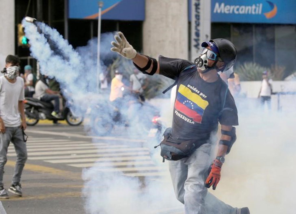 Manifestante de oposição arremessa de volta granada de gás lacrimogêneo lançada pela polícia durante protesto. 19/04/2017 REUTERS/Marco Bello (Foto: Aquiles Lins) Manifestante de oposição arremessa de volta granada de gás lacrimogêneo lançada pela polícia durante protesto. 19/04/2017 REUTERS/Marco Bello