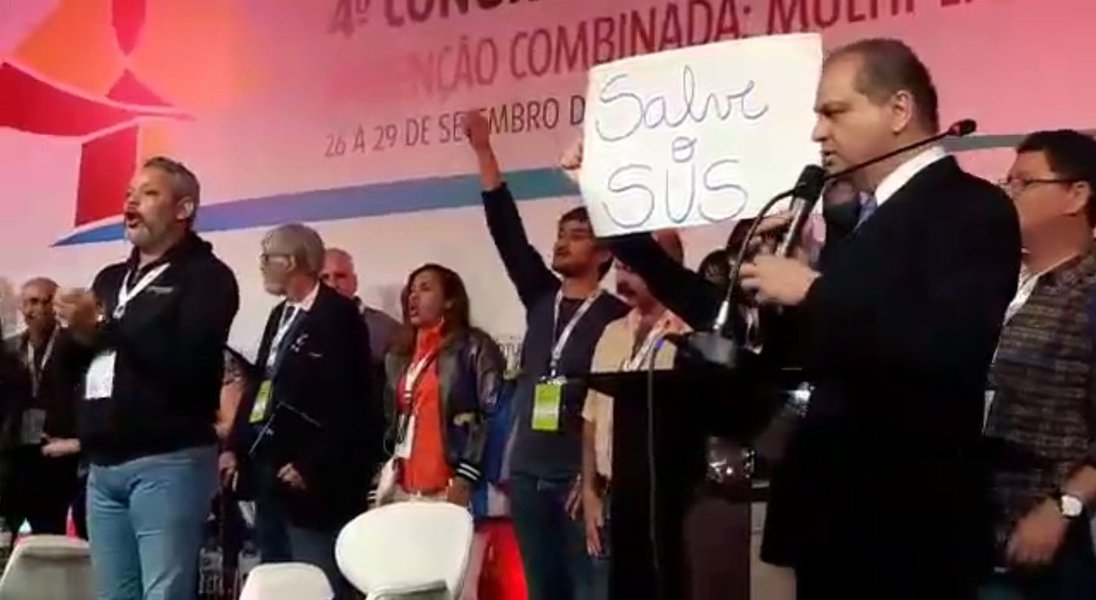 O ministro da Saúde, Ricardo Barros, teve o discurso interrompido por manifestantes nesta sexta-feira (29) durante o 11º Congresso de HIV/Aids e 4º Congresso de Hepatites Virais (HepAids 2017), que acontece em Curitiba; portando cartazes com dizeres “Salve o SUS”, “Nenhum Direito a Menos”, os manifestantes gritavam “Fora Temer” e o “SUS é nosso, ninguém tira da gente!” (Foto: Charles Nisz) O ministro da Saúde, Ricardo Barros, teve o discurso interrompido por manifestantes nesta sexta-feira (29) durante o 11º Congresso de HIV/Aids e 4º Congresso de Hepatites Virais (HepAids 2017), que acontece em Curitiba; portando cartazes com dizeres “Salve o SUS”, “Nenhum Direito a Menos”, os manifestantes gritavam “Fora Temer” e o “SUS é nosso, ninguém tira da gente!”