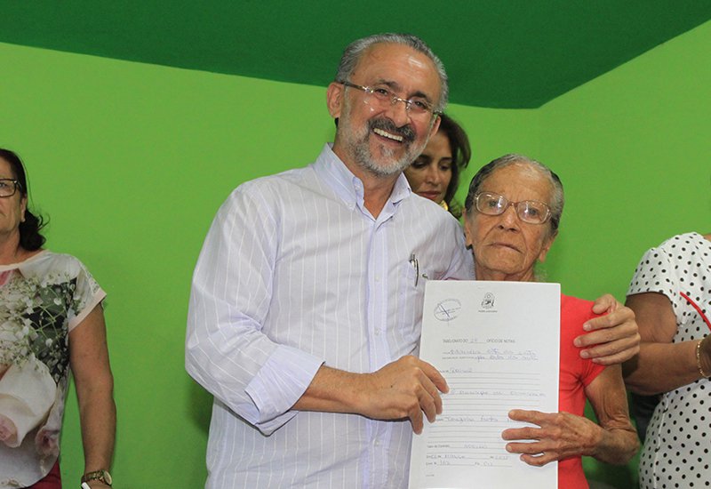 O prefeito de Camaçari, Ademar Delgado, entregou nesta quarta-feira 370 escrituras públicas a moradores de 13 bairros e localidades do município, por meio do 'Programa Municipal de Regularização Fundiária'; ele destacou a importância da escritura para fazer melhorias no imóvel, por exemplo, uma vez que de posse do documento é possível pleitear linhas de financiamento para reformas junto aos bancos; "Agora vocês podem bater no peito e dizer 'A casa é minha!', de fato e de direito. Já que acabaram de receber o documento registrado em cartório" (Foto: Romulo Faro) O prefeito de Camaçari, Ademar Delgado, entregou nesta quarta-feira 370 escrituras públicas a moradores de 13 bairros e localidades do município, por meio do 'Programa Municipal de Regularização Fundiária'; ele destacou a importância da escritura para fazer melhorias no imóvel, por exemplo, uma vez que de posse do documento é possível pleitear linhas de financiamento para reformas junto aos bancos; "Agora vocês podem bater no peito e dizer 'A casa é minha!', de fato e de direito. Já que acabaram de receber o documento registrado em cartório"