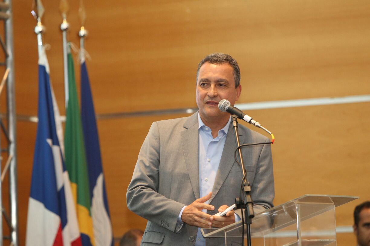 O governador Rui Costa defendeu a desoneração do PIS e da Cofins, pagos ao governo federal, sobre o abastecimento de água, o que geraria para a empresa pública de abastecimento do Estado, segundo ele, até R$ 250 milhões anuais de economia; defesa foi feita no XVIII Encontro Nacional de Comitês de Bacias Hidrográficas, aberto na noite desta segunda (4); "Não faz o menor sentido onerar a distribuição de água para a população rural, no semiárido e de baixa renda. No nosso estado, isso seria uma economia de até 250 milhões por ano, que poderia ser investida na preservação dos mananciais. Se tivéssemos esse recurso para financiar a própria manutenção da água na Bahia, seria de grande ajuda", disse Rui (Foto: Romulo Faro) O governador Rui Costa defendeu a desoneração do PIS e da Cofins, pagos ao governo federal, sobre o abastecimento de água, o que geraria para a empresa pública de abastecimento do Estado, segundo ele, até R$ 250 milhões anuais de economia; defesa foi feita no XVIII Encontro Nacional de Comitês de Bacias Hidrográficas, aberto na noite desta segunda (4); "Não faz o menor sentido onerar a distribuição de água para a população rural, no semiárido e de baixa renda. No nosso estado, isso seria uma economia de até 250 milhões por ano, que poderia ser investida na preservação dos mananciais. Se tivéssemos esse recurso para financiar a própria manutenção da água na Bahia, seria de grande ajuda", disse Rui