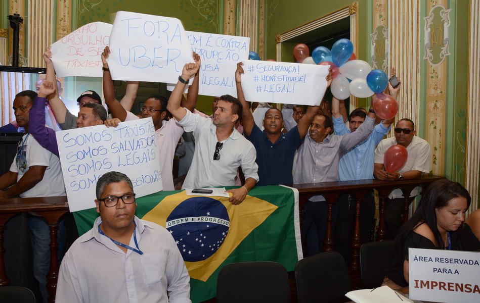 Com a galeria da Câmara tomada por taxistas na sessão ordinária desta quarta-feira, os vereadores aprovaram por unanimidade o projeto de lei de autoria de Alfredo Mangueira (PMDB) que proíbe o funcionamento do Uber em Salvador; proibição ao serviço particular de transporte, segundo Mangueira, "justifica-se por ser uma concorrência desleal e perigosa" com o serviço tradicional de táxi. Ele argumenta que o sistema é clandestino, e "vende a falsa ideia de um transporte seguro, confortável e rápido aos usuários" (Foto: Romulo Faro) Com a galeria da Câmara tomada por taxistas na sessão ordinária desta quarta-feira, os vereadores aprovaram por unanimidade o projeto de lei de autoria de Alfredo Mangueira (PMDB) que proíbe o funcionamento do Uber em Salvador; proibição ao serviço particular de transporte, segundo Mangueira, "justifica-se por ser uma concorrência desleal e perigosa" com o serviço tradicional de táxi. Ele argumenta que o sistema é clandestino, e "vende a falsa ideia de um transporte seguro, confortável e rápido aos usuários"
