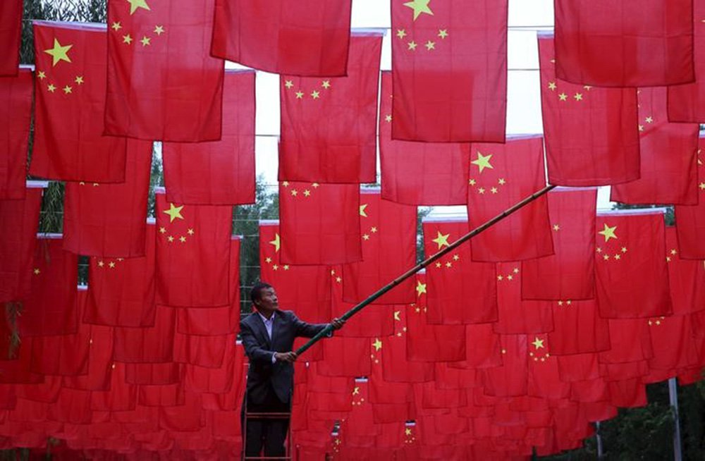 Homem colocando bandeiras chinesas em parque em Pequim. 29/09/2015 REUTERS/China Daily (Foto: Paulo Emílio) Homem colocando bandeiras chinesas em parque em Pequim. 29/09/2015 REUTERS/China Daily
