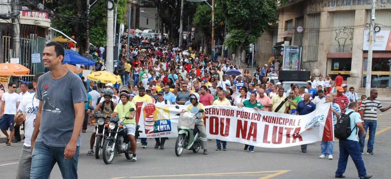 Os servidores da prefeitura de Salvador decidiram manter a greve que teve início no dia 15 de março; decisão foi tomada em assembleia da categoria nesta sexta-feira; após a reunião, os servidores saíram em caminhada até a sede da prefeitura; a categoria exige o desbloqueio dos vencimentos de fevereiro, que foram bloqueados pelo prefeito ACM Neto; segundo o coordenador do Sindseps, Bruno Carianha, a expectativa é de que "o prefeito faça o imediato desbloqueio dos salários, bem como garanta a retomada das negociações, relacionadas à campanha salarial 2016, principalmente dos pontos referentes às pautas não financeiras que possibilite melhores condições de trabalho aos servidores" (Foto: Romulo Faro) Os servidores da prefeitura de Salvador decidiram manter a greve que teve início no dia 15 de março; decisão foi tomada em assembleia da categoria nesta sexta-feira; após a reunião, os servidores saíram em caminhada até a sede da prefeitura; a categoria exige o desbloqueio dos vencimentos de fevereiro, que foram bloqueados pelo prefeito ACM Neto; segundo o coordenador do Sindseps, Bruno Carianha, a expectativa é de que "o prefeito faça o imediato desbloqueio dos salários, bem como garanta a retomada das negociações, relacionadas à campanha salarial 2016, principalmente dos pontos referentes às pautas não financeiras que possibilite melhores condições de trabalho aos servidores"