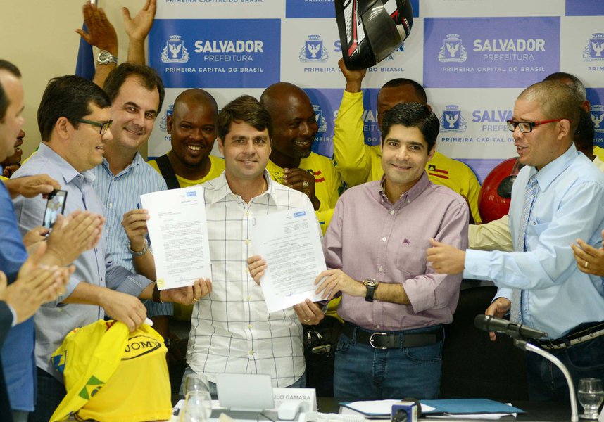 O projeto de lei que regulamenta a atividade de mototáxi em Salvador foi assinado pelo prefeito ACM Neto e entregue ao presidente da Câmara Municipal, vereador Paulo Câmara, em cerimônia nesta quarta-feira; "O que a gente vê hoje é que existem muitos serviços de mototáxi em Salvador, só que realizados sem qualquer fiscalização e controle do poder municipal e que trazem, por exemplo, problemas de segurança para o usuário. Hoje apresentamos um projeto que é bom para o mototaxista, que vai poder realizar a atividade e desempenhar a profissão de maneira oficial, reconhecida pelo poder público e sem o sentimento de ameaça de impedimento de exercer a atividade, pois há muitos pais e mães de família envolvidos com a profissão", disse ACM (Foto: Romulo Faro) O projeto de lei que regulamenta a atividade de mototáxi em Salvador foi assinado pelo prefeito ACM Neto e entregue ao presidente da Câmara Municipal, vereador Paulo Câmara, em cerimônia nesta quarta-feira; "O que a gente vê hoje é que existem muitos serviços de mototáxi em Salvador, só que realizados sem qualquer fiscalização e controle do poder municipal e que trazem, por exemplo, problemas de segurança para o usuário. Hoje apresentamos um projeto que é bom para o mototaxista, que vai poder realizar a atividade e desempenhar a profissão de maneira oficial, reconhecida pelo poder público e sem o sentimento de ameaça de impedimento de exercer a atividade, pois há muitos pais e mães de família envolvidos com a profissão", disse ACM