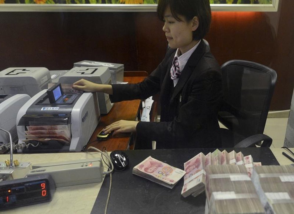 Funcionária conta notas de 100 iuanes em agência bancária na China. 20/04/2015 REUTERS/Stringer (Foto: Gisele Federicce) Funcionária conta notas de 100 iuanes em agência bancária na China. 20/04/2015 REUTERS/Stringer