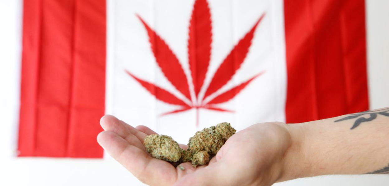 An employee holds marijuana in front of a modified Canadian flag with a marijuana leaf while posing in a photo illustration at a dispensary in Ottawa, Ontario, Canada, June 20, 2018. REUTERS/Chris Wattie - RC114C203B70 (Foto: Chris Wattie) An employee holds marijuana in front of a modified Canadian flag with a marijuana leaf while posing in a photo illustration at a dispensary in Ottawa, Ontario, Canada, June 20, 2018. REUTERS/Chris Wattie - RC114C203B70