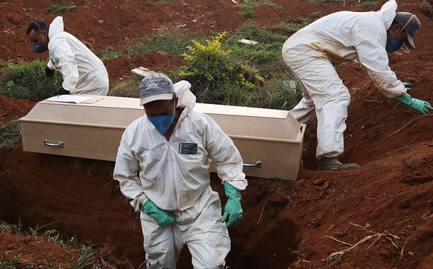 Coveiros com trajes de proteção enterram pessoa que morreu infectatada pelo novo coronavírus (Foto: REUTERS/Amanda Perobelli) Coveiros com trajes de proteção enterram pessoa que morreu infectatada pelo novo coronavírus