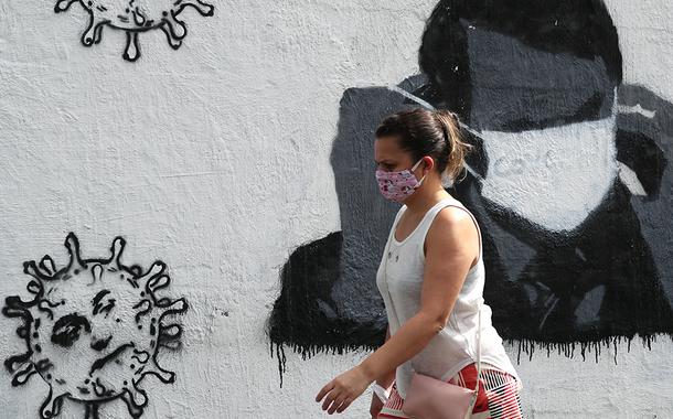 Mulher passa por grafite do presidente Jair Bolsonaro ajustando sua máscara protetora e em forma de vírus, em meio ao surto de Covid-19 no Rio de Janeiro. (Foto: REUTERS/Sergio Moraes) Mulher passa por grafite do presidente Jair Bolsonaro ajustando sua máscara protetora e em forma de vírus, em meio ao surto de Covid-19 no Rio de Janeiro.
