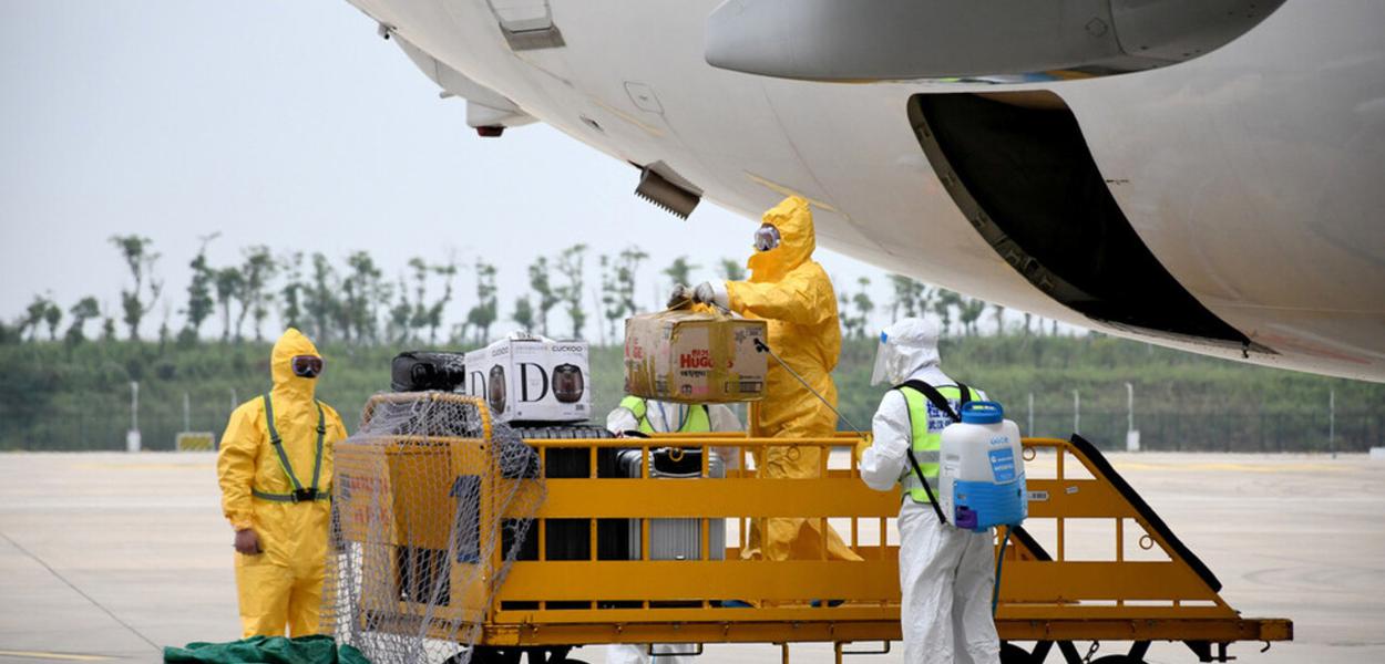 Trabalhadores em trajes de proteção desinfetam bagagens que chegam no Aeroporto Internacional de Wuhan (Foto: Reuters) Trabalhadores em trajes de proteção desinfetam bagagens que chegam no Aeroporto Internacional de Wuhan