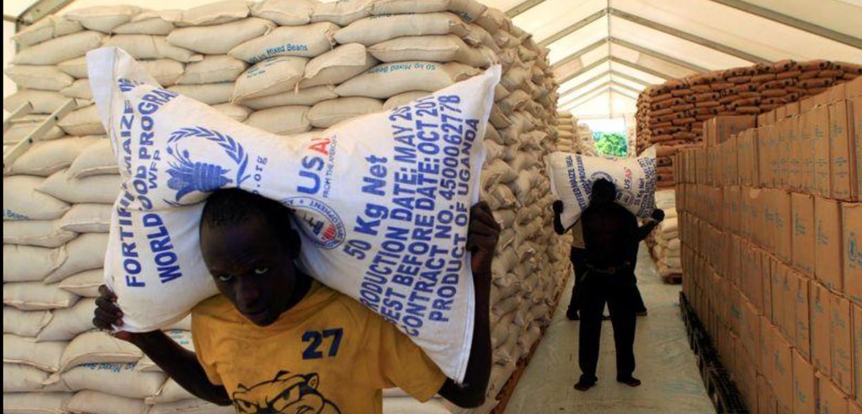 Pessoas carregam sacos de alimentos do Programa Mundial de Alimentos da ONU em assentamento para refugiados do Sudão do Sul em Uganda (Foto: REUTERS/James Akena) Pessoas carregam sacos de alimentos do Programa Mundial de Alimentos da ONU em assentamento para refugiados do Sudão do Sul em Uganda