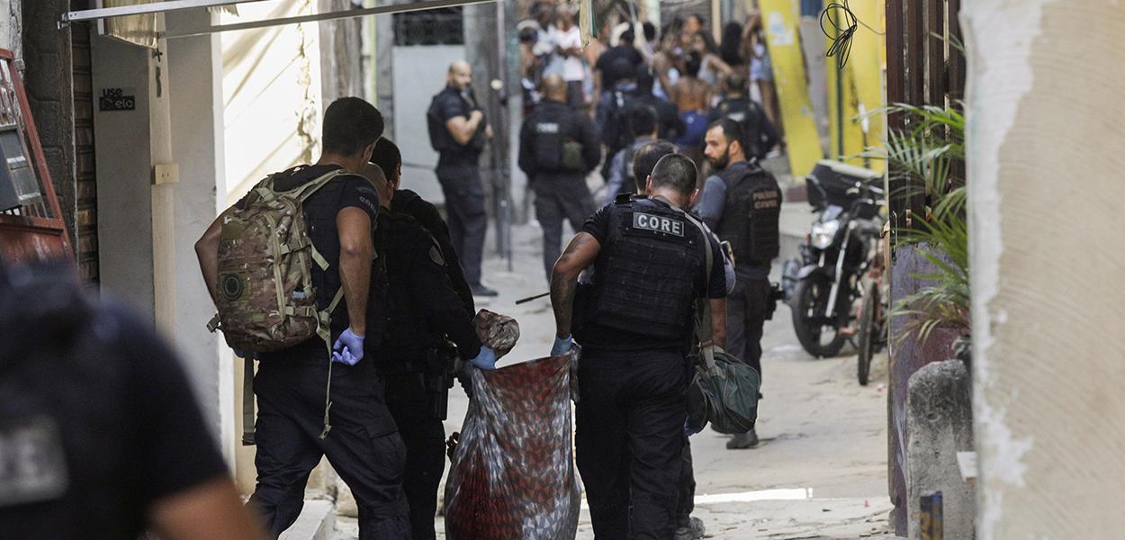 Policiais carregam corpo durante operação na favela do Jacarezinho 06/05/2021 (Foto: REUTERS/Ricardo Moraes) www.brasil247.com - Policiais carregam corpo durante operação na favela do Jacarezinho 06/05/2021