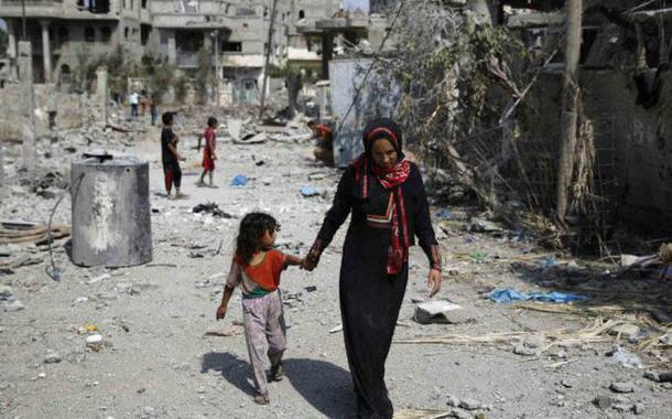 Palestina caminha com criança por prédios destruídos ao norte da Faixa de Gaza (Foto: Finbarr OReilly/Reuters) Palestina caminha com criança por prédios destruídos ao norte da Faixa de Gaza