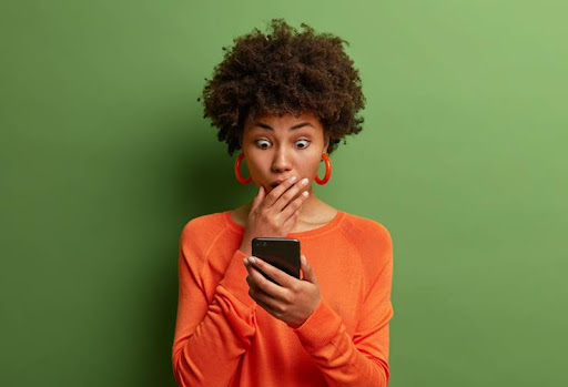 Horizontal shot of amazed adult woman being deeply surprised, stares at smartphone display, reads shocking news on website, dressed in orange jumper, has bugged eyes, covers mouth. Omg, its horrible! (Foto: Divulgação) Horizontal shot of amazed adult woman being deeply surprised, stares at smartphone display, reads shocking news on website, dressed in orange jumper, has bugged eyes, covers mouth. Omg, its horrible!