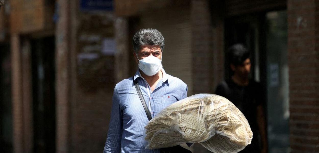 Um homem iraniano segura pilhas de pão enquanto caminha por uma rua em Teerã, Irã, 1º de maio de 2022 (Foto: Majid Asgaripour/WANA (Agência de Notícias da Ásia Ocidental) via REUTERS) www.brasil247.com - Um homem iraniano segura pilhas de pão enquanto caminha por uma rua em Teerã, Irã, 1º de maio de 2022