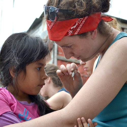 Above, a Christendom College student teaches a child about the Miraculous Medal in Costa Rica; below, Franciscan University students pray for the dead and leave flowers at a local cemetery. Above, a Christendom College student teaches a child about the Miraculous Medal in Costa Rica; below, Franciscan University students pray for the dead and leave flowers at a local cemetery.