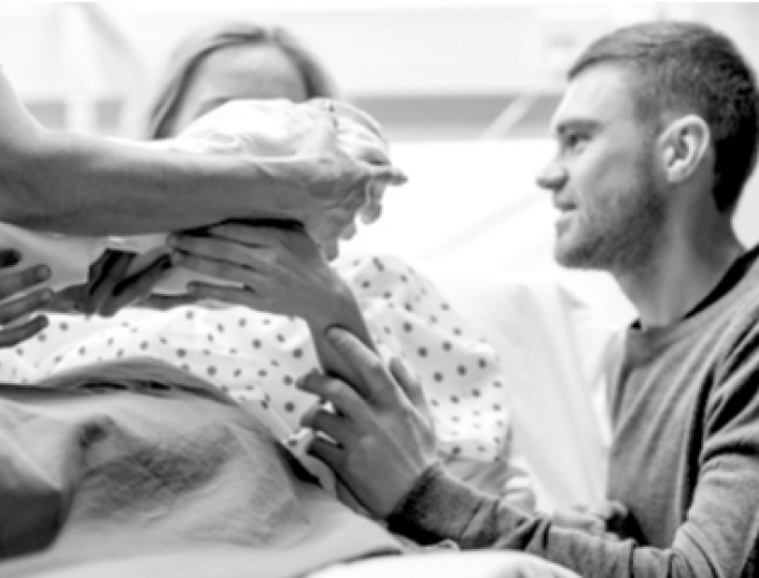 A midwife hands a newborn to her parents. A midwife hands a newborn to her parents.