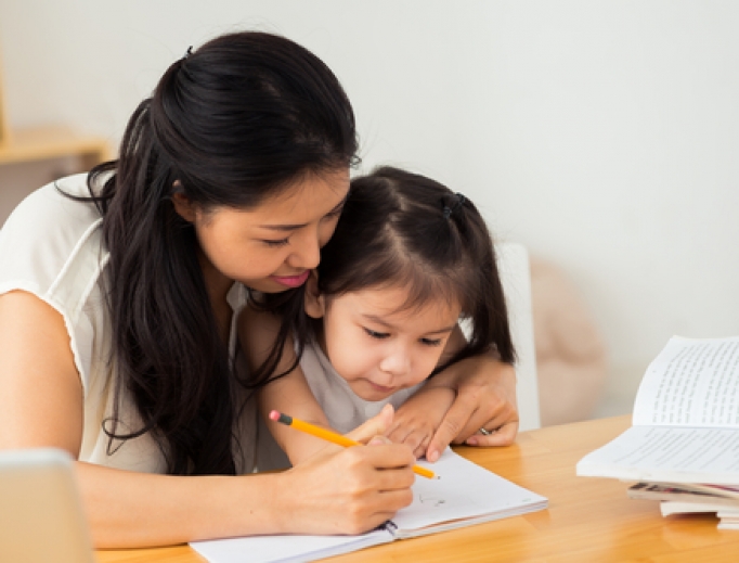 Mother teaching her young daughter how to write. Mother teaching her young daughter how to write.