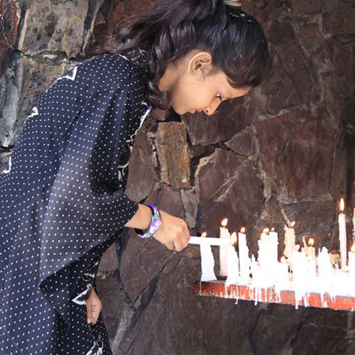 A young girl lights a candle at a Marian grotto in Pakistan. A young girl lights a candle at a Marian grotto in Pakistan.
