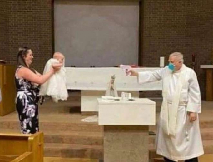 Fr. Stephen Klasek pretends to shoot water at a baby in this now-viral photo. Fr. Stephen Klasek pretends to shoot water at a baby in this now-viral photo.
