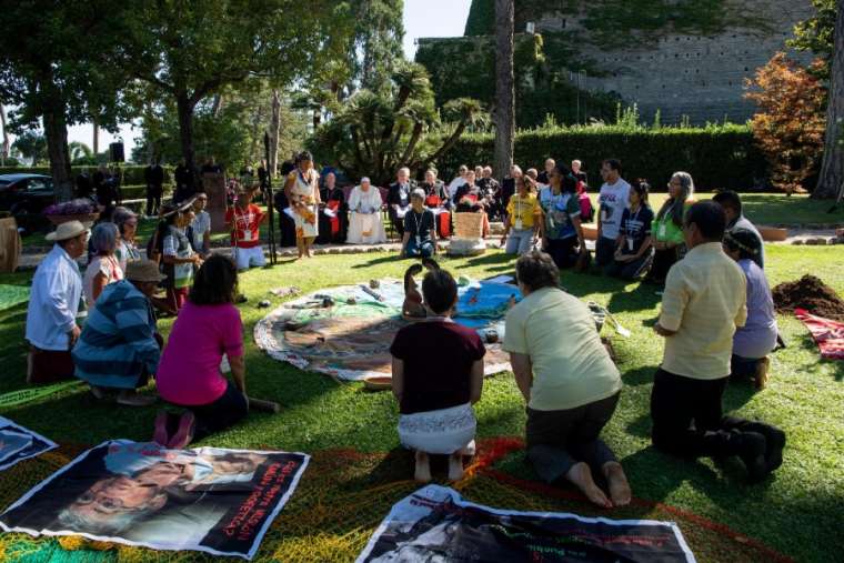 Participants kneel before bowing to a set of items during a tree-planting ceremony in the Vatican Gardens Oct. 3. Participants kneel before bowing to a set of items during a tree-planting ceremony in the Vatican Gardens Oct. 3.