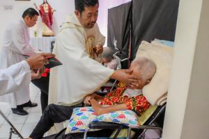 A priest anoints a very sick patient in a hospital. A priest anoints a very sick patient in a hospital.