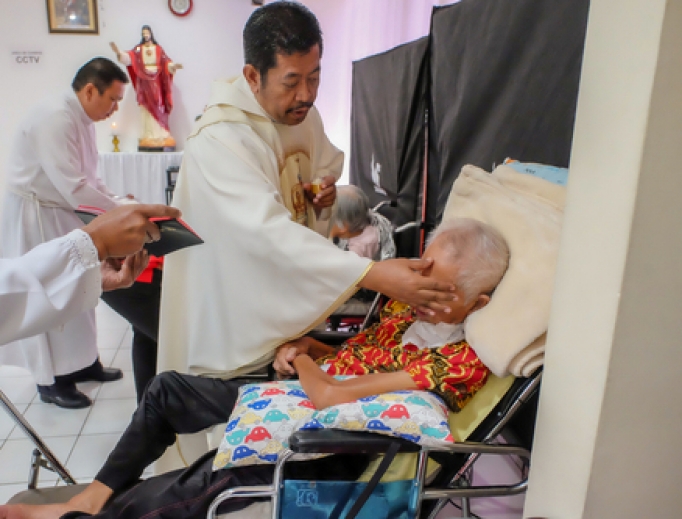 A priest anoints a very sick patient in a hospital. A priest anoints a very sick patient in a hospital.