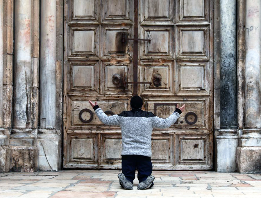 A man kneels in prayer in front of the closed doors of the Church of the Holy Sepulcher in Jerusalem April 9, during the COVID-19 pandemic lockdown. A man kneels in prayer in front of the closed doors of the Church of the Holy Sepulcher in Jerusalem April 9, during the COVID-19 pandemic lockdown.