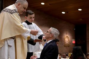 Above, Father John Mosimann, pastor of St. Mary of the Immaculate Conception parish in Fredericksburg, Virginia, gives David Bereit Communion during the Easter vigil Mass. Below, the Bereit family celebrates the new Catholic with Father Mosimann. Above, Father John Mosimann, pastor of St. Mary of the Immaculate Conception parish in Fredericksburg, Virginia, gives David Bereit Communion during the Easter vigil Mass. Below, the Bereit family celebrates the new Catholic with Father Mosimann.