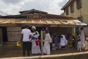 A mother holds her baby while speaking to a man about the construction of her home in Lagos, Nigeria. A mother holds her baby while speaking to a man about the construction of her home in Lagos, Nigeria.