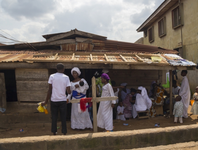 A mother holds her baby while speaking to a man about the construction of her home in Lagos, Nigeria. A mother holds her baby while speaking to a man about the construction of her home in Lagos, Nigeria.