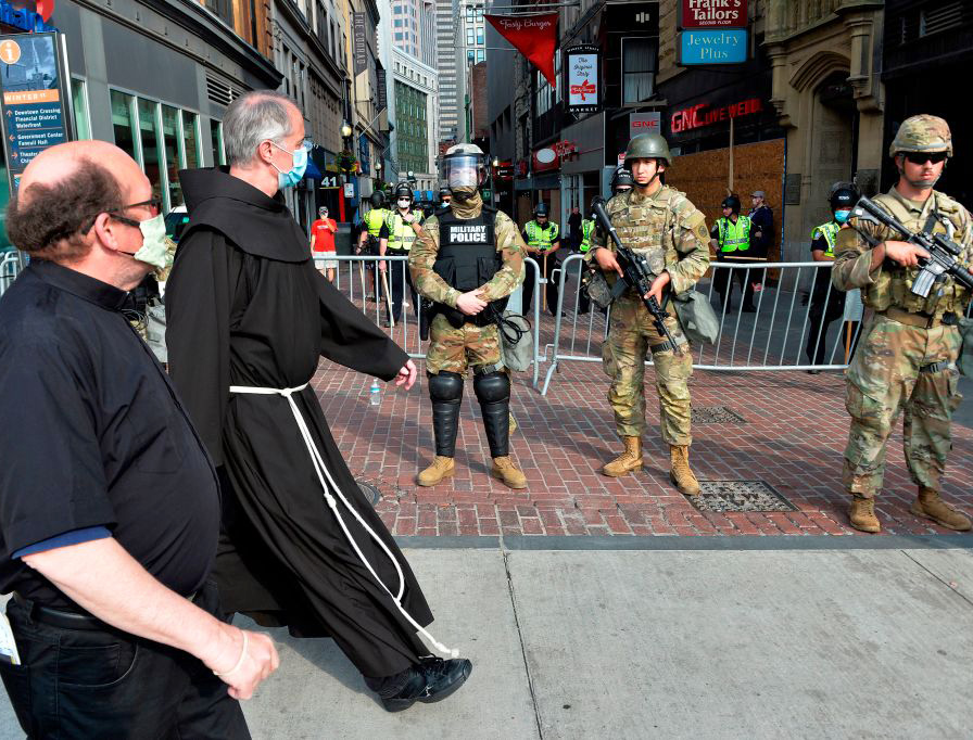 Two priests walk by National Guard Soldiers stationed in downtown Boston on Wednesday. Two priests walk by National Guard Soldiers stationed in downtown Boston on Wednesday.