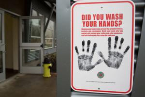 Above, a sign reminding people to wash their hands is pictured outside a dormitory at the Washington State Patrol Fire Training Academy, which has been designated as a coronavirus quarantine site for travelers from Hubei Province, China. Below, Dr./Deacon Timothy Flanigan sanitizes his hands at a Liberia medical clinic. Dr. Flanigan is an infectious disease specialist at the medical school at Brown University and assisted with the recent Ebola outbreak.
Above, a sign reminding people to wash their hands is pictured outside a dormitory at the Washington State Patrol Fire Training Academy, which has been designated as a coronavirus quarantine site for travelers from Hubei Province, China. Below, Dr./Deacon Timothy Flanigan sanitizes his hands at a Liberia medical clinic. Dr. Flanigan is an infectious disease specialist at the medical school at Brown University and assisted with the recent Ebola outbreak.