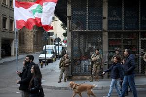 Army soldiers look on as Lebanese anti-government protesters march toward the capital in Beirut's downtown district Jan. 25. The political impasse is worsening an already-dire economic crisis in Lebanon that the World Bank says may see the number of people living in poverty climb from a third to half the population. Army soldiers look on as Lebanese anti-government protesters march toward the capital in Beirut's downtown district Jan. 25. The political impasse is worsening an already-dire economic crisis in Lebanon that the World Bank says may see the number of people living in poverty climb from a third to half the population.