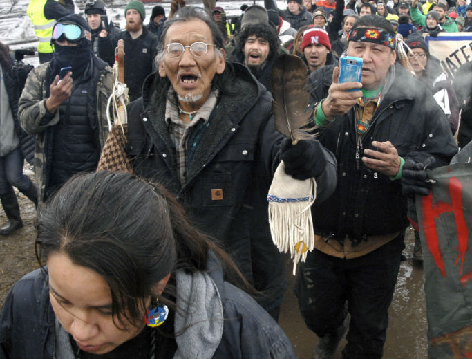 In this 2017, file photo,Nathan Phillips (center with glasses), marches out of the Oceti Sakowin camp before the deadline set for evacuation of the camp near Cannon Ball, North Dakota. Phillips was part of a large crowd representing a majority of the remaining Dakota Access Pipeline protesters, A source close to the leadership of the National Basilica of the Shrine of the Immaculate Conception in Washington corroborated an eyewitness account that saw Phillips and a group of activists tried to enter the church during Mass while playing drums and chanting. They were prohibited from entering the building by security personnel, who locked the main basilica doors with the congregation still inside. In this 2017, file photo,Nathan Phillips (center with glasses), marches out of the Oceti Sakowin camp before the deadline set for evacuation of the camp near Cannon Ball, North Dakota. Phillips was part of a large crowd representing a majority of the remaining Dakota Access Pipeline protesters, A source close to the leadership of the National Basilica of the Shrine of the Immaculate Conception in Washington corroborated an eyewitness account that saw Phillips and a group of activists tried to enter the church during Mass while playing drums and chanting. They were prohibited from entering the building by security personnel, who locked the main basilica doors with the congregation still inside.