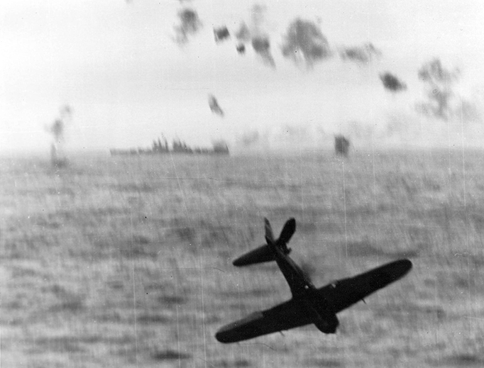 A Japanese Zero Kamikaze crashes into the sea after trying to hit the aircraft carrier USS Essex (CV-9) off Okinawa, May 14, 1945. The vessel in the background is a U.S. Navy Cleveland-class light cruiser. A Japanese Zero Kamikaze crashes into the sea after trying to hit the aircraft carrier USS Essex (CV-9) off Okinawa, May 14, 1945. The vessel in the background is a U.S. Navy Cleveland-class light cruiser.
