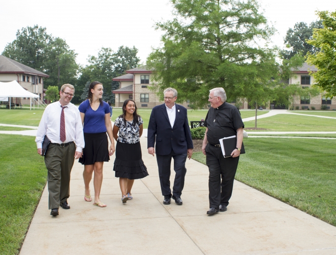Holy Cross Father David Tyson chats with faculty and students; also shown: more students and the campus chapel Holy Cross Father David Tyson chats with faculty and students; also shown: more students and the campus chapel