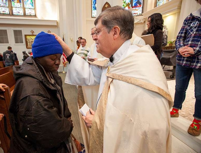 Father Ron Cattany blesses an attendee of the annual Father Woody Christmas cash giveaway, Dec. 14. Father Ron Cattany blesses an attendee of the annual Father Woody Christmas cash giveaway, Dec. 14.