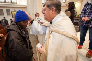 Father Ron Cattany blesses an attendee of the annual Father Woody Christmas cash giveaway, Dec. 14. Father Ron Cattany blesses an attendee of the annual Father Woody Christmas cash giveaway, Dec. 14.