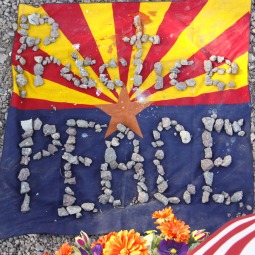 'PRACTICE PEACE.' An Arizona and U.S. flag with stones is seen at the memorial outside the offices of Rep. Gabrielle Giffords in Tucson, Ariz., Jan. 11. Giffords suffered a gunshot wound to the head in a shooting spree that killed six people. 'PRACTICE PEACE.' An Arizona and U.S. flag with stones is seen at the memorial outside the offices of Rep. Gabrielle Giffords in Tucson, Ariz., Jan. 11. Giffords suffered a gunshot wound to the head in a shooting spree that killed six people.